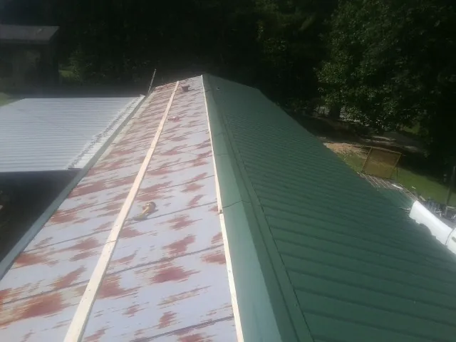 Old rusted panels beside newly installed green metal roofing — Wind Damage Roof Repair by Roofing Brothers in Renville