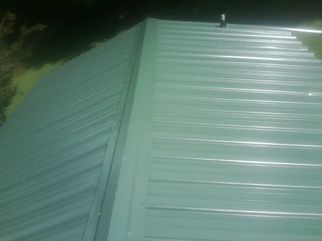 New green metal panels meeting at the ridge of a roof — Flat Roof Repair work by our crew in Renville