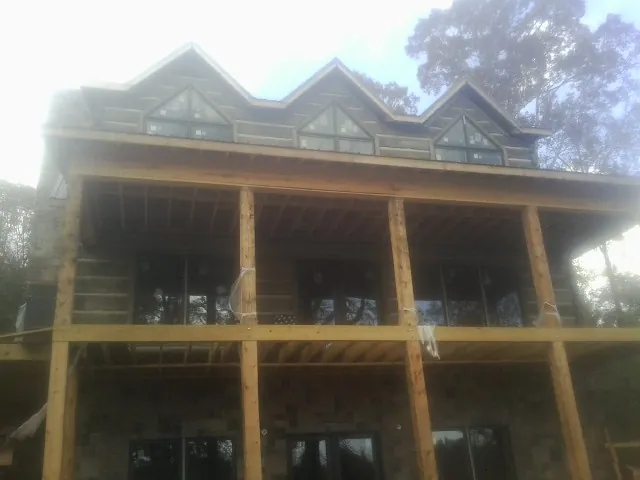 Dormers and porch framing on a large log home under construction — Roof Coating work by our crew in Renville
