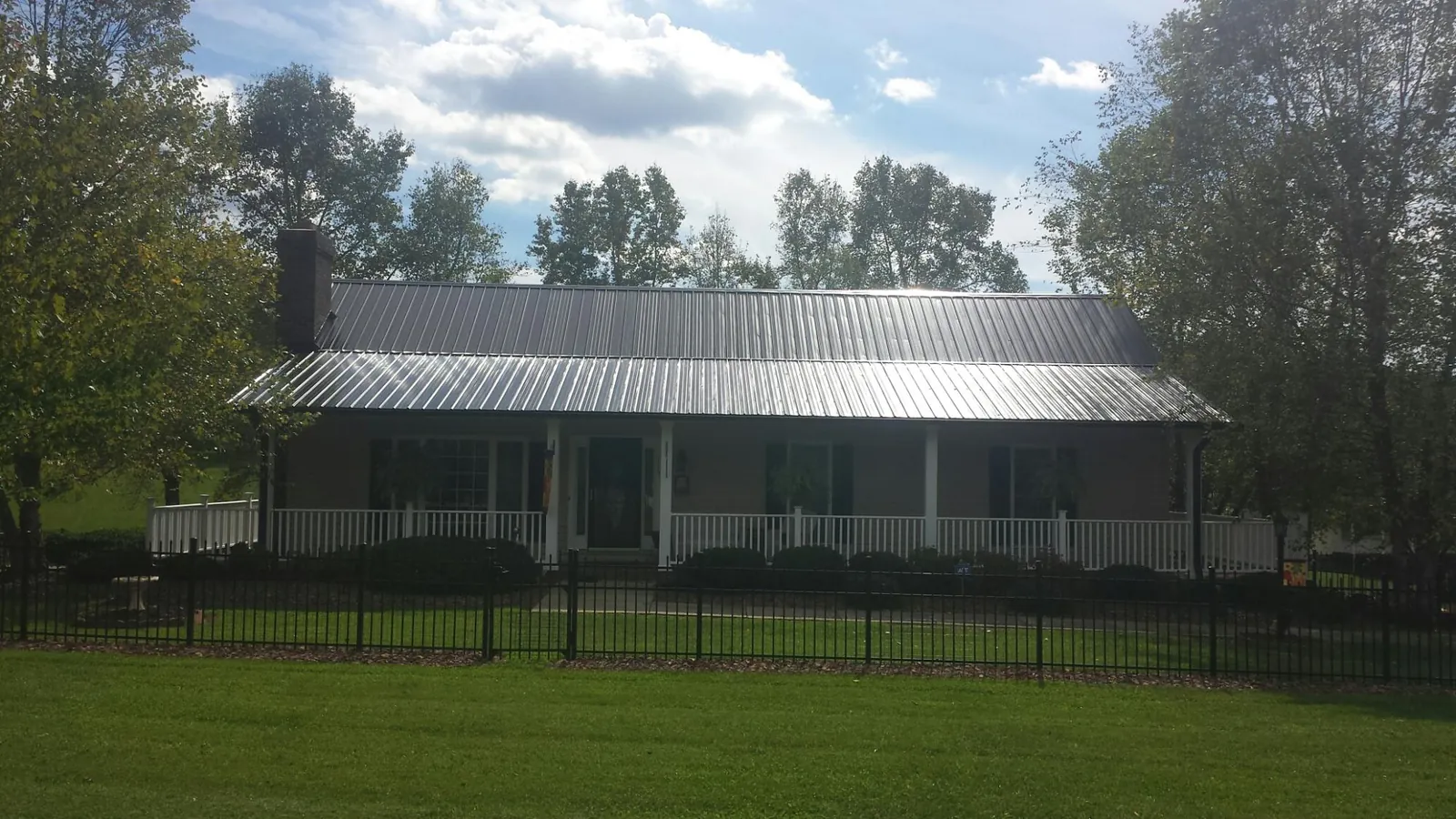 Gray metal roof on a brick ranch with a full width front porch — Gutter Guard Installation work by our crew in Renville