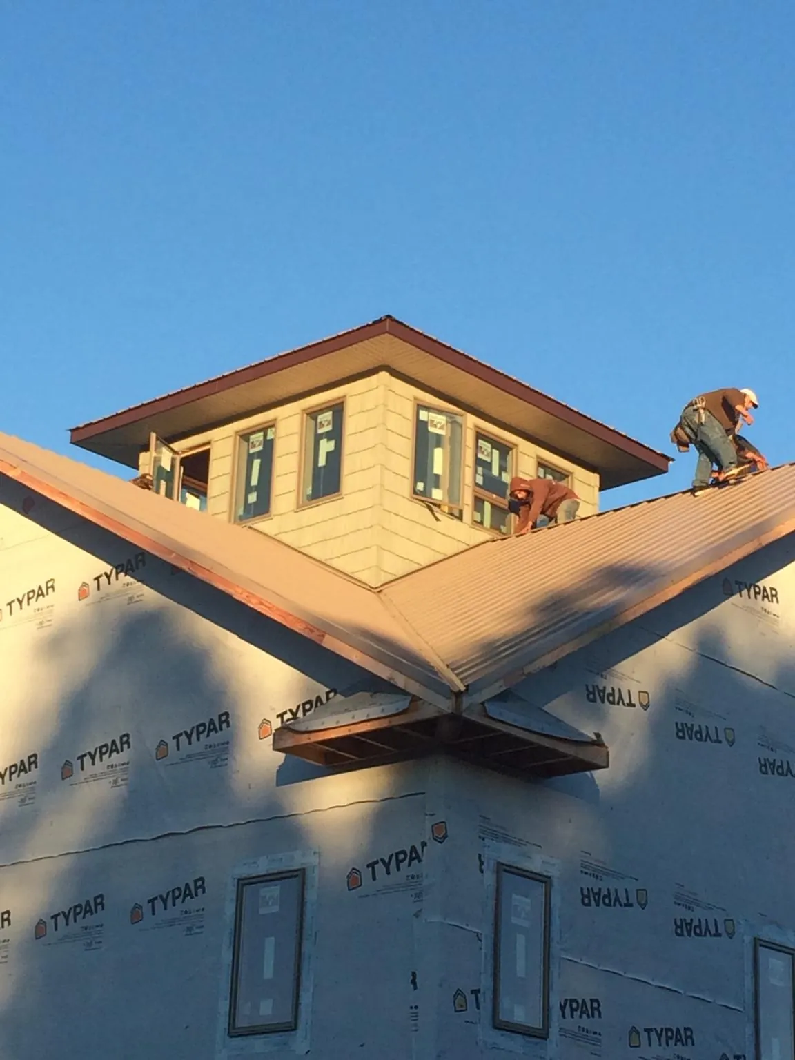 Roofers working around a rooftop cupola on a new metal roof at sunset — Roof Waterproofing in Renville by Roofing Brothers